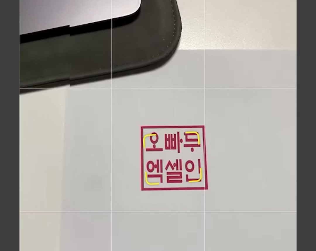 휴대폰 카메라 PHOTO 모드 화면 가운데에 A4 용지의 오빠두 엑셀인 도장이 크게 잡힌 장면
